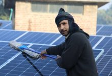 A man cleans solar panels on the roof of a building